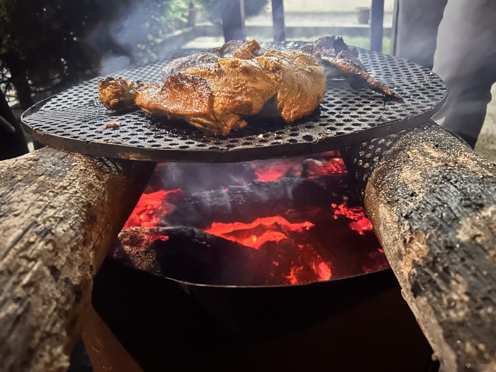 Pollo dorado sobre la parrilla, justo encima de las brasas al rojo vivo.