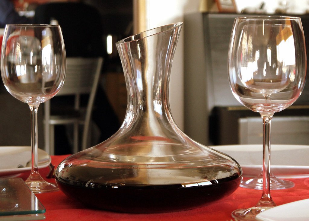 Decantador y copas de vino tinto sobre el mantel, en el comedor de Alma.