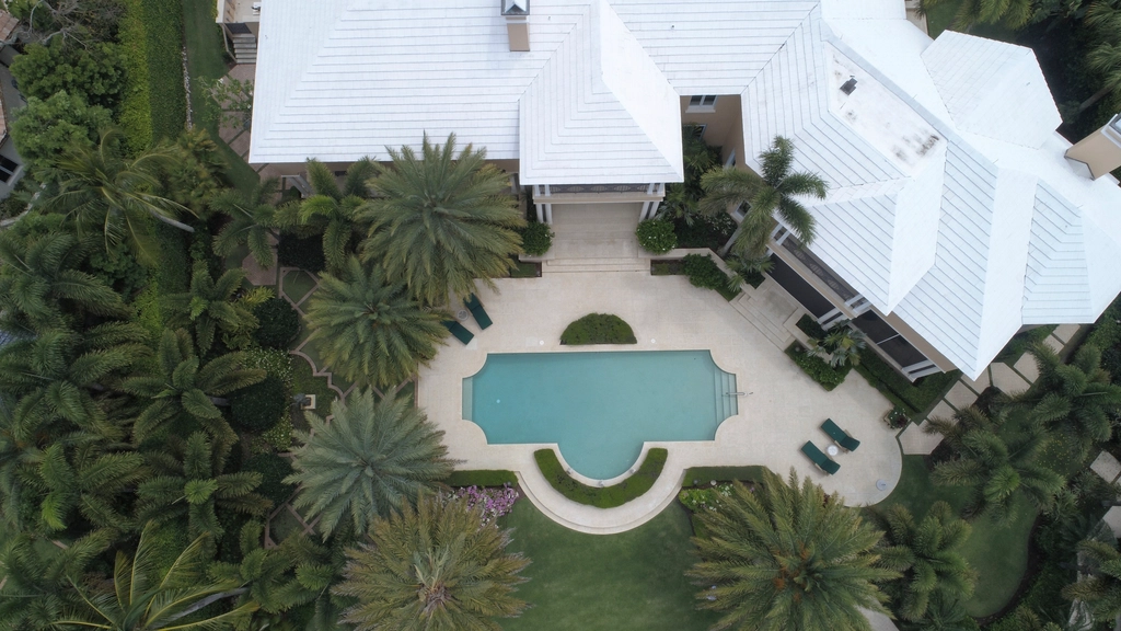 Vista aérea de una villa contemporánea con alberca y jardín, al atardecer