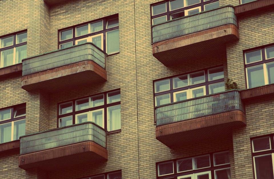 Detalle de fachada residencial con balcones de hormigón y barandales de vidrio