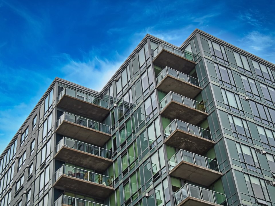 Fachada de una torre residencial contemporánea vista en contrapicado, con balcones y paños de hormigón blanco